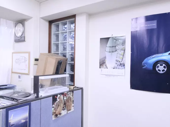 取引先企業のポスターやカレンダー、社員旅行時の写真が飾られています。