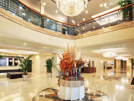新老夫婦とご家族、参列者をお迎えする高級感と落ち着きが漂うホテルのエントランス。