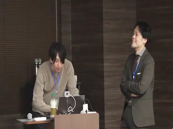 管理本部の上司になる三輪と麻生です。 年に２回全社員を集めた社員総会の準備中の1枚です。