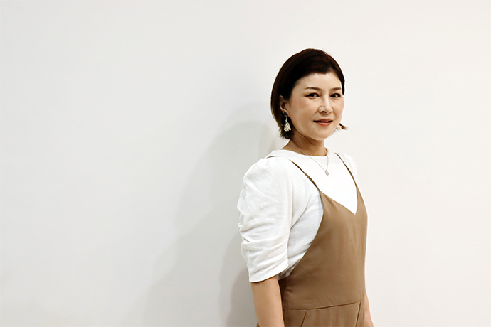 白い壁の前でほほ笑む落語家の三遊亭あら馬さん
